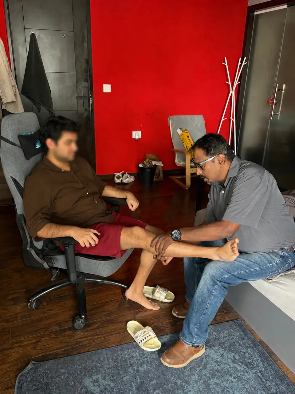 A Physova physiotherapist assessing a patient's leg during a home visit